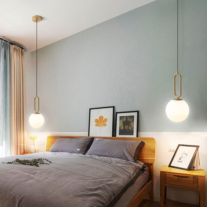 Modern ball pendant hanging light installed beside bed, adding stylish ambient lighting to contemporary bedroom