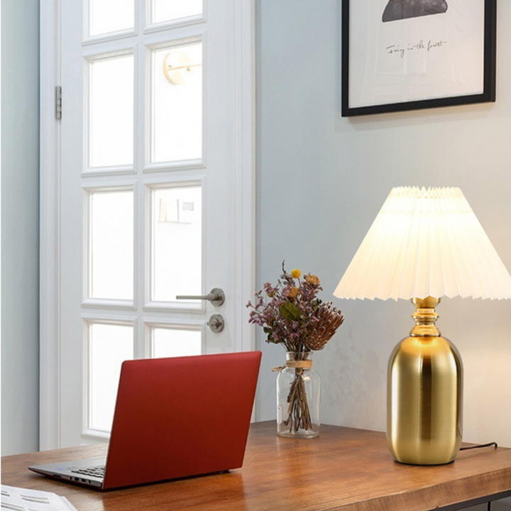 Modern bedside lamp with cylinder metal base glowing softly on tabletop