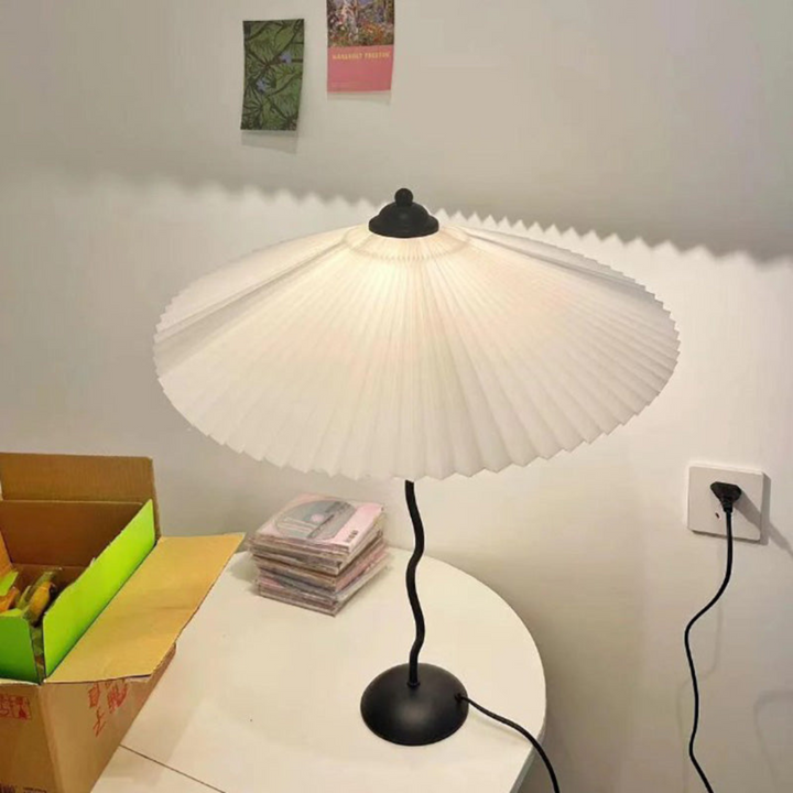 Folded-shade modern table lamp glowing softly in cozy room