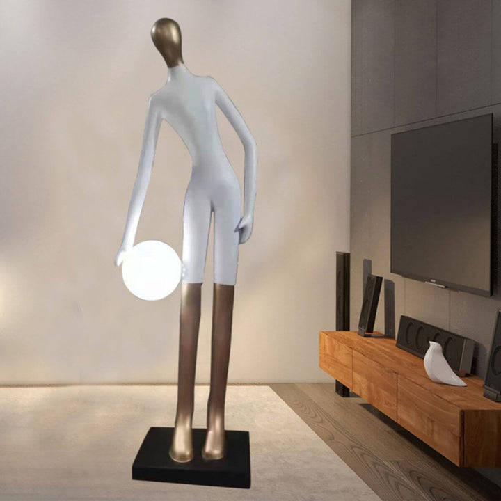 White statue floor lamp holding a glowing light globe, combining sculpture and ambient lighting
