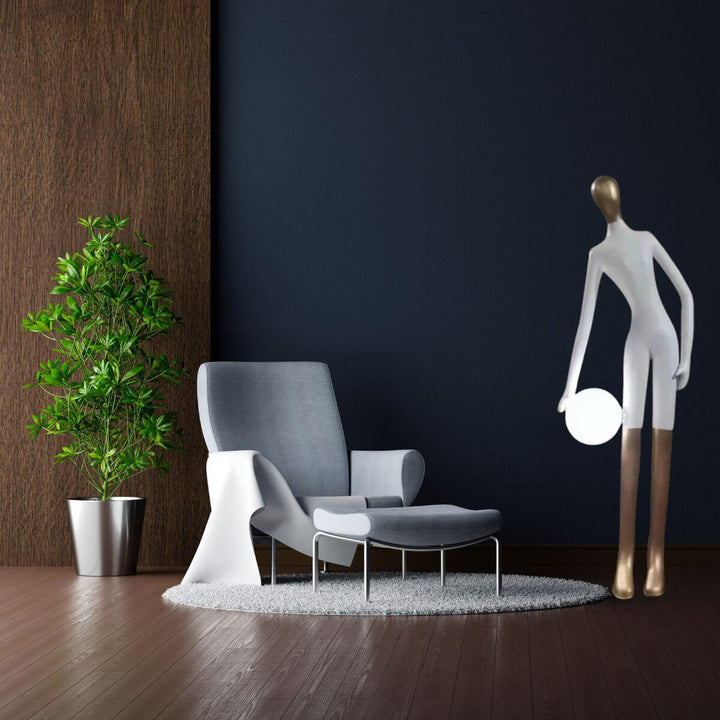 White statue floor lamp holding light globe placed beside sofa set, blending art with ambient lighting