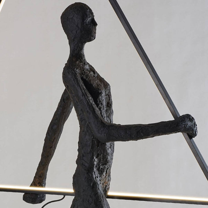 Side view of human statue floor lamp with triangle design and warm lighting