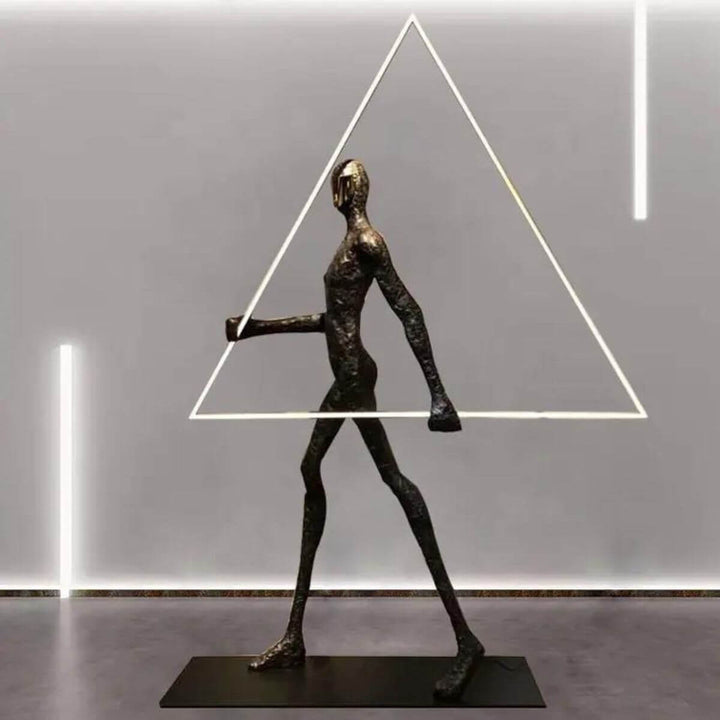 Side view of human statue floor lamp with triangle design and warm lighting