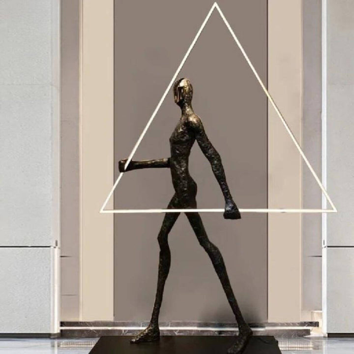 Side view of human statue floor lamp featuring a geometric triangle element, combining modern sculpture with ambient lighting