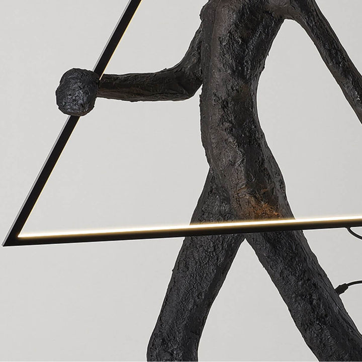 Close-up detail view of human statue floor lamp with geometric triangle design, highlighting intricate sculpture and lighting feature