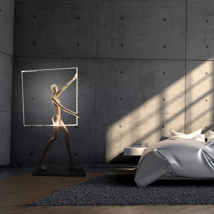 Romeo statue LED floor lamp placed beside a bed, combining artistic sculpture with warm ambient lighting for a cozy bedroom setting