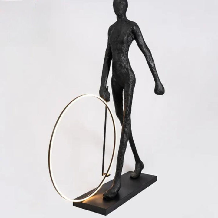 Angled view of a man walking beside a modern circle LED floor lamp, showcasing the glowing ring and sleek design in a contemporary interior