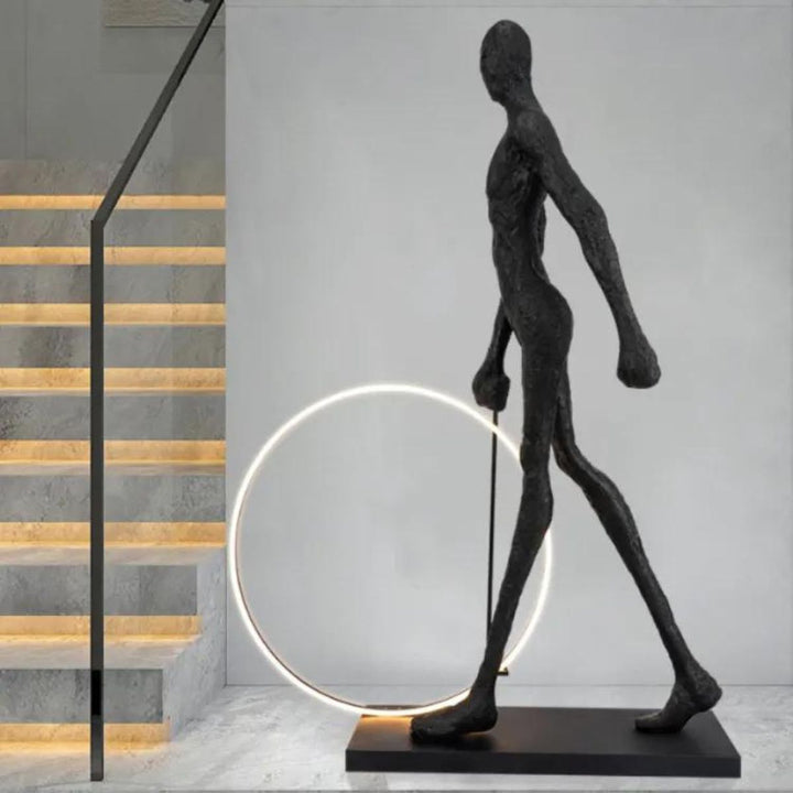 Man walking next to a modern circle LED floor lamp, featuring a glowing circular frame and contemporary interior design