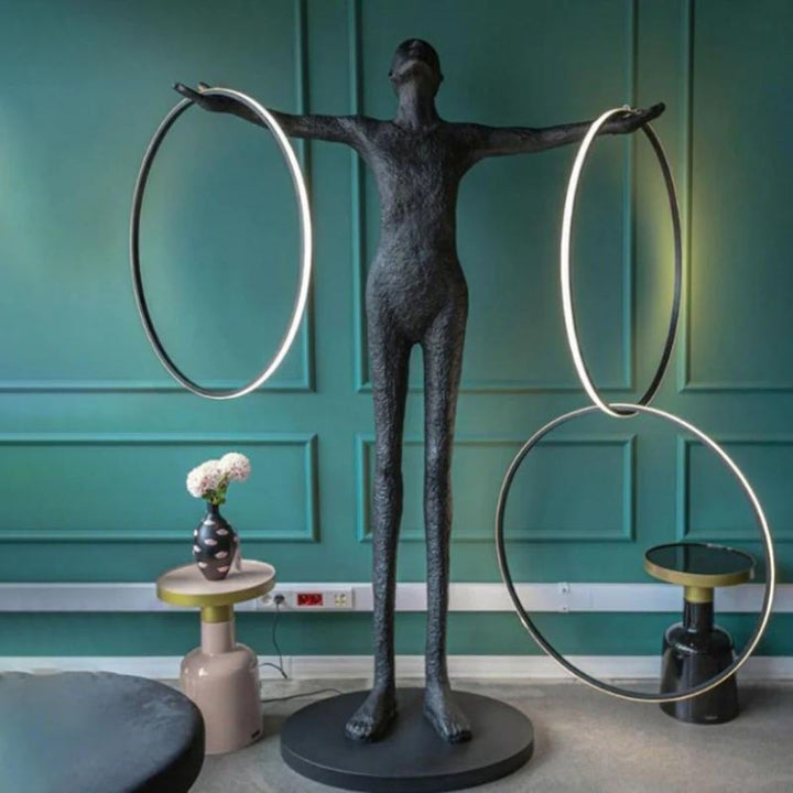 Human posing beside a burning circle LED floor lamp in a modern living room, highlighting warm ambient lighting and contemporary interior design
