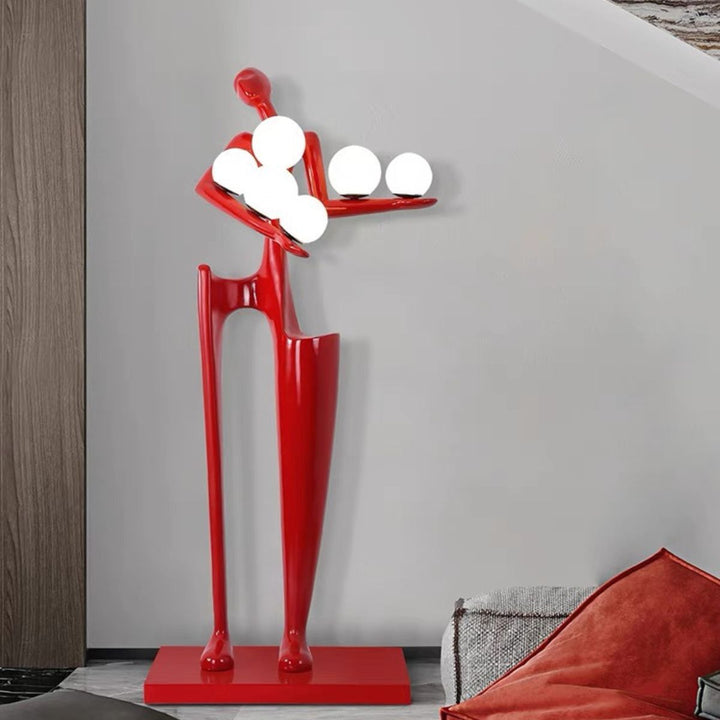 Dreamer red statue sculpture holding illuminated globes, blending vibrant color with modern artistic lighting design
