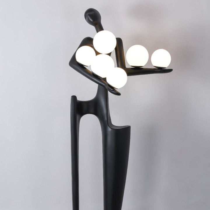 Half view of Dreamer black statue sculpture holding glass globes, highlighting the upper body and artistic design details