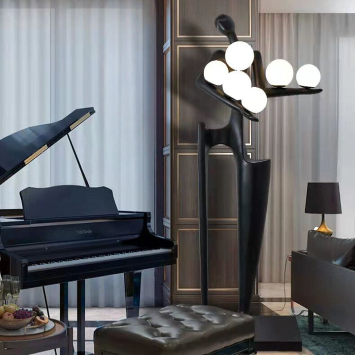 Side view of Dreamer black statue holding globes positioned against a wall, showcasing elegant sculptural details and modern design