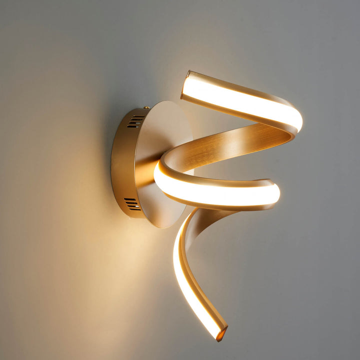 Lara gold spiral LED wall light installed on table side wall in elegant interior setting
