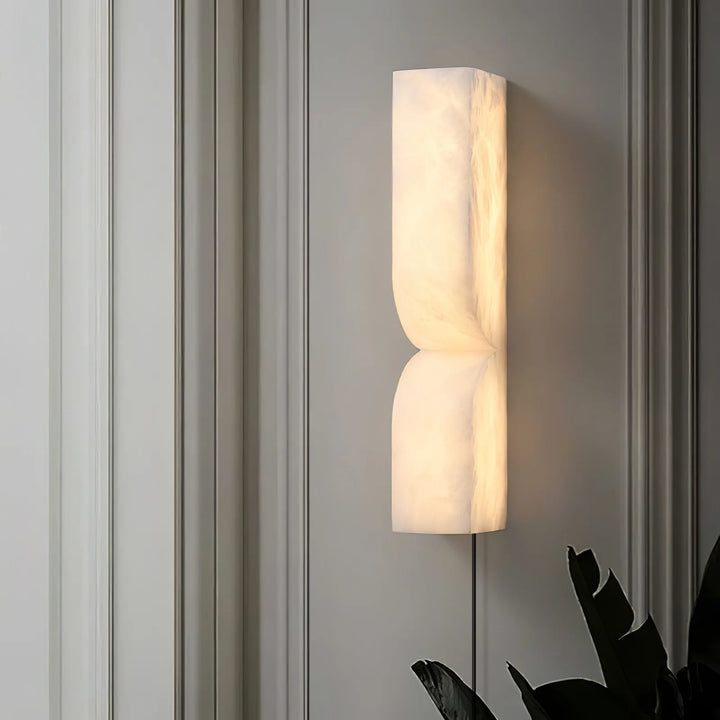 Front view of Alabaster Essence plug-in marble wall sconce with light on for elegant décor