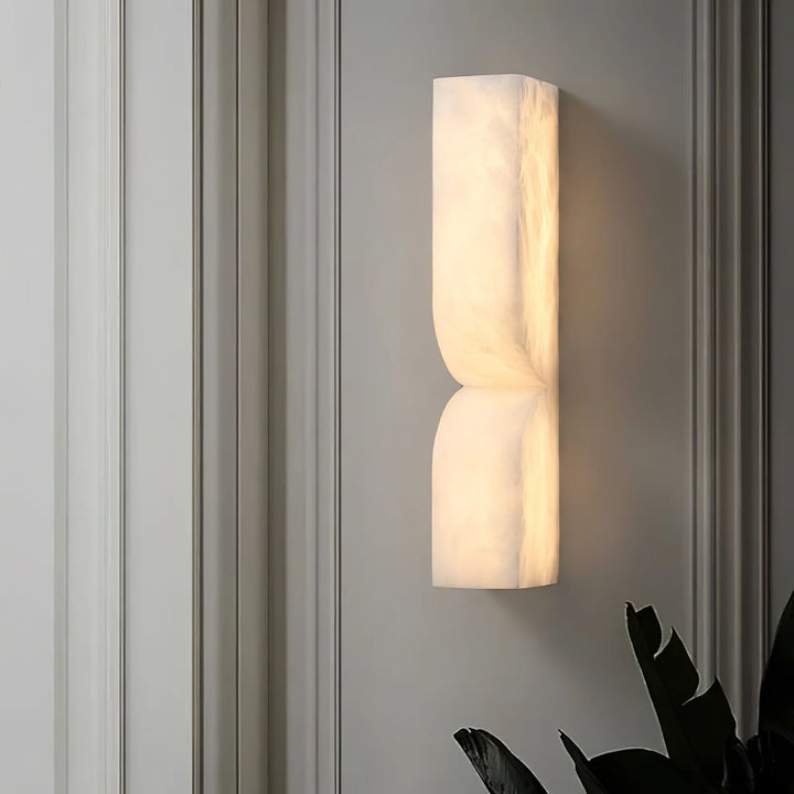 Modern side perspective of Alabaster Essence plug-in wall sconce with light on