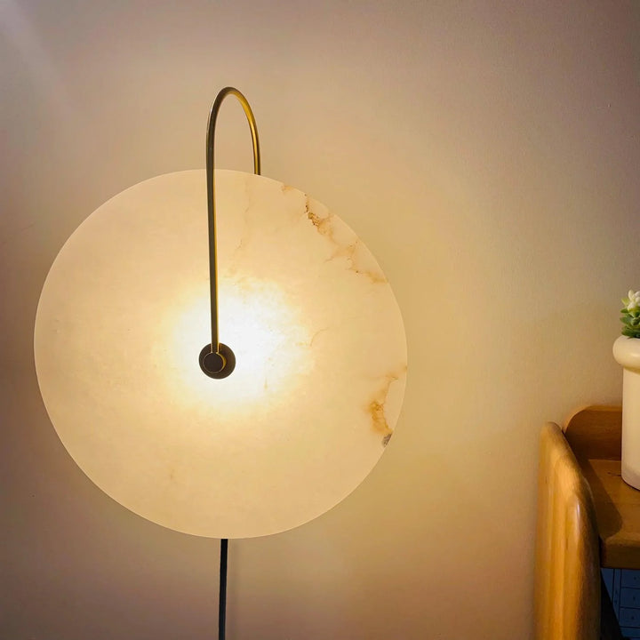 Front view of alabaster LED plug-in wall lamp with warm light and natural veining pattern
