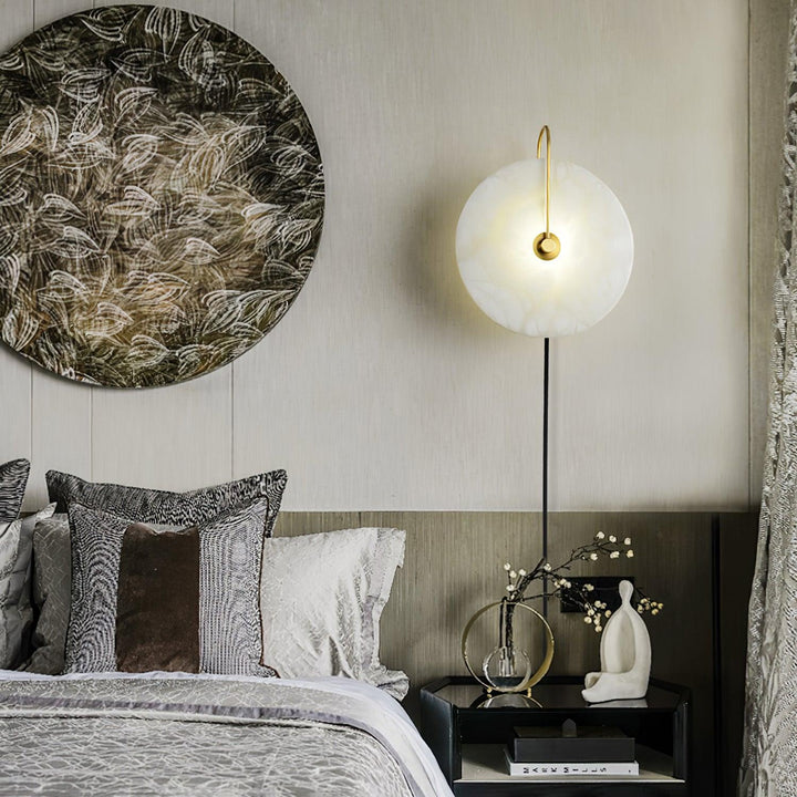 Bedside view of alabaster LED plug-in wall lamp with warm diffused light and natural veining.