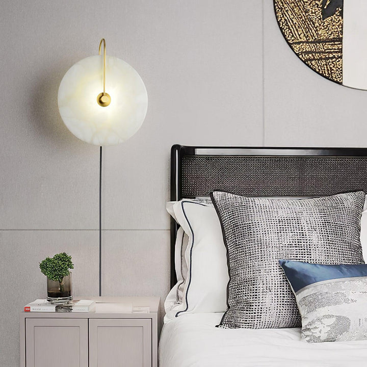Bedside view of alabaster LED plug-in wall lamp with warm light and natural veining