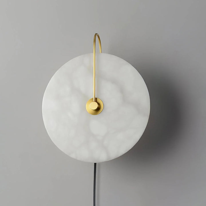 Front view alabaster LED plug-in wall lamp with warm light and golden metal base contrast