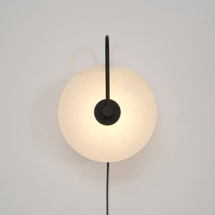 Front view of alabaster LED plug-in wall lamp with natural veining and warm diffuse light