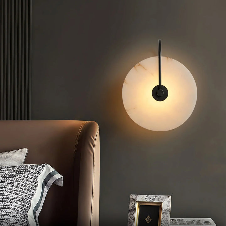 Bedside view alabaster LED plug-in wall lamp with warm light and natural stone veining.