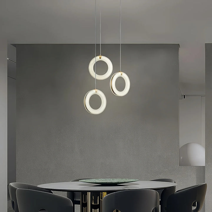 Hanging perspective of trio of modern alabaster ring pendant lights over dining area