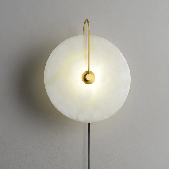 Side angle view alabaster LED plug-in wall lamp with warm diffuse light and unique stone veining.