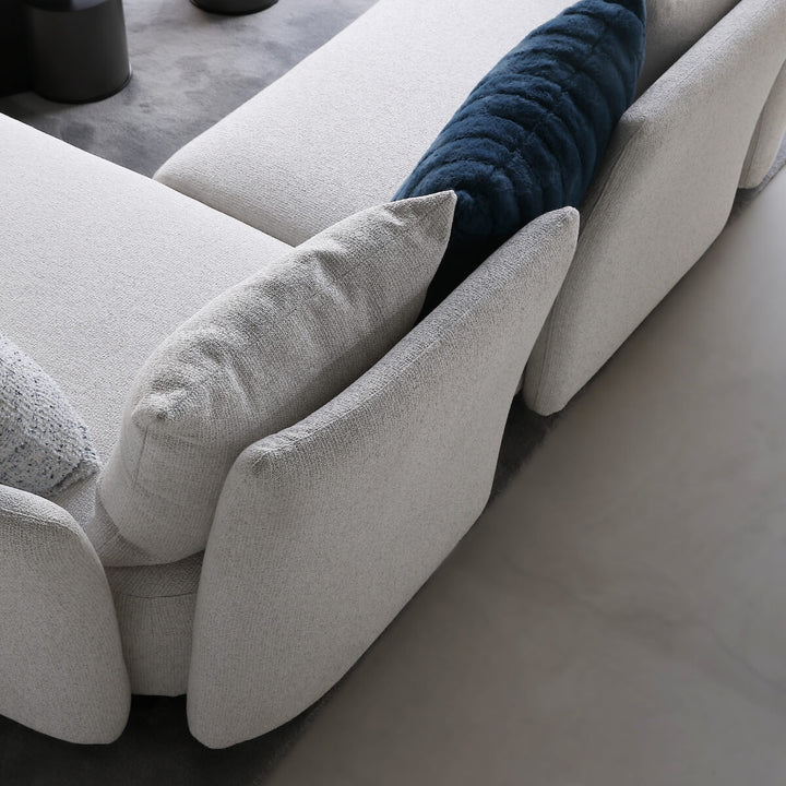 Side close-up of Coastal Curve sofa lounge showing curved armrest and soft fabric upholstery.