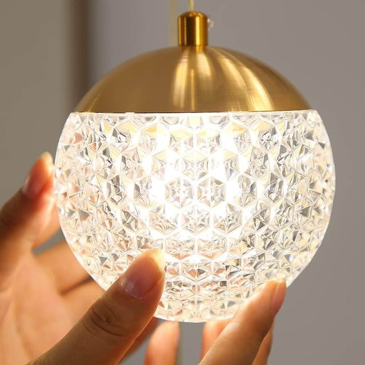 Crystal prism pendant light with gold finish and integrated LED, offering elegant illumination for modern interiors