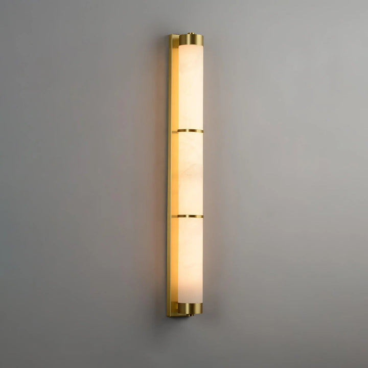 Cylindra alabaster brass wall light illuminated, showcasing elegant modern design in interior setting