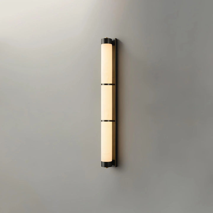 Cylindra alabaster brass wall light shown from front view in sleek modern interior setting
