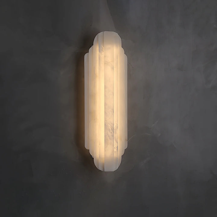 Side view of Estelle alabaster wall sconce lighting, showcasing its refined shape and warm glow.