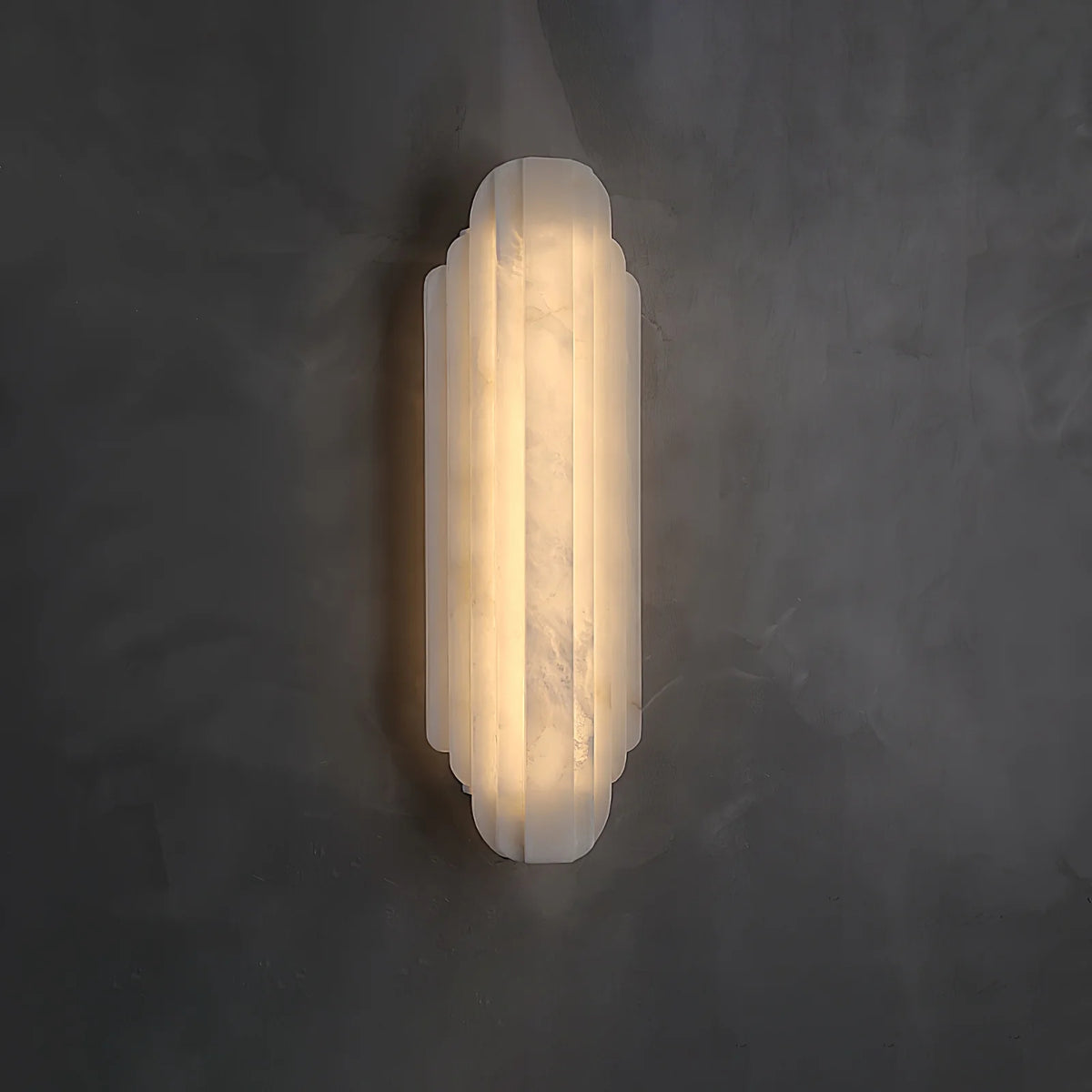 Side view of Estelle alabaster wall sconce lighting, showcasing its refined shape and warm glow.