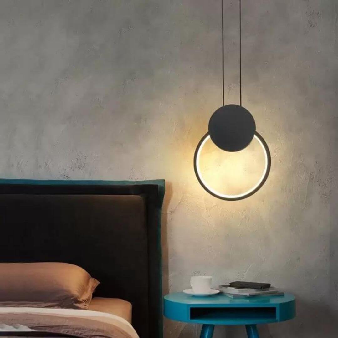 Gleam Circular Pendant Light hanging above bedside table, providing soft, focused lighting with minimalist modern elegance.