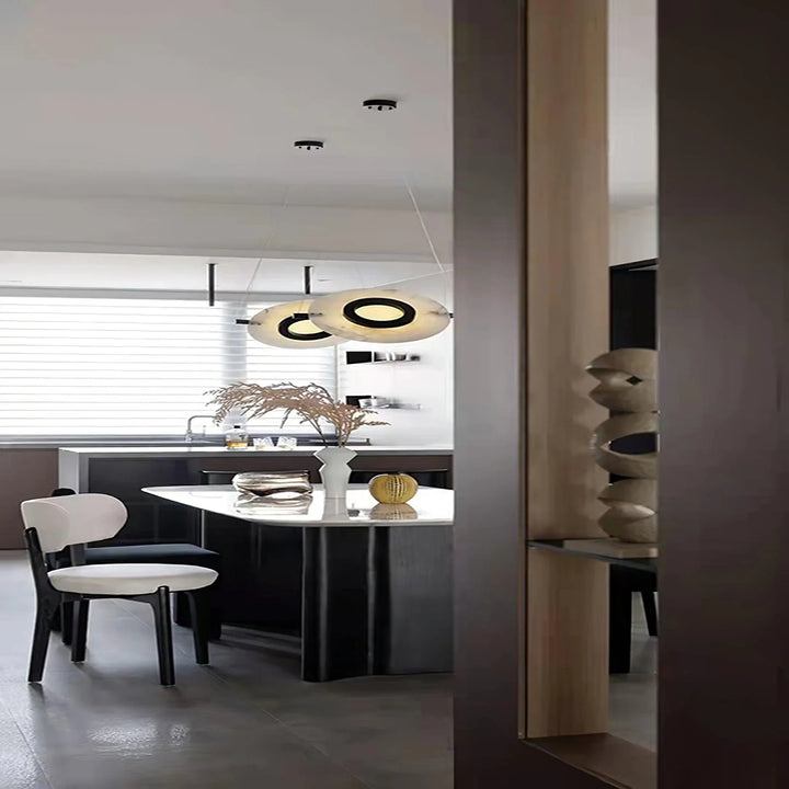 Magma pendant lamp hanging above dining table with black exterior and glowing gold interior