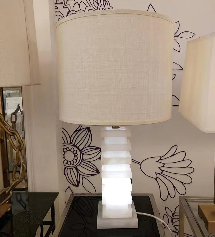 Front view of stacked alabaster table lamp with stone blocks base and linen shade, modern lighting