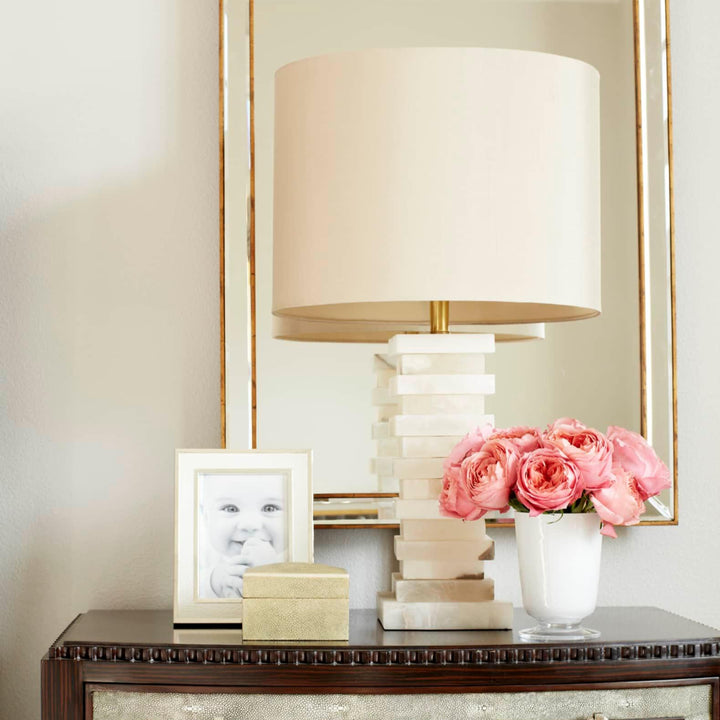 Modern stacked alabaster table lamp with layered stone base and fabric shade, warm ambient light