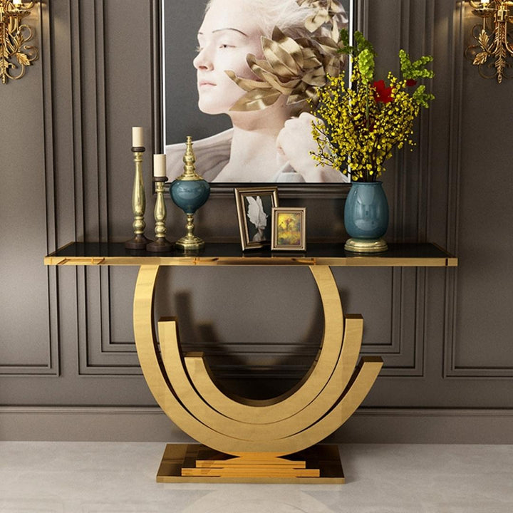Front view of Lidia console table with sleek black glass top and elegant gold frame in a modern interior setting